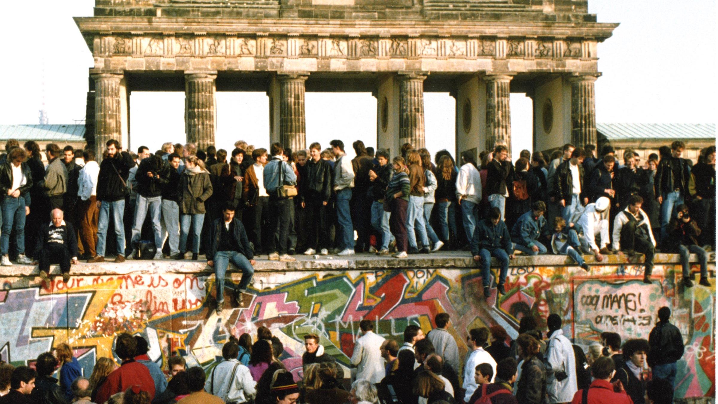 "Der letzte Sommer der DDR (3)": Am Tag nach der Öffnung am 9. November 1989 steigen Menschen am 10. November 1989 auf die Berliner Mauer vor dem Brandenburger Tor in Berlin.