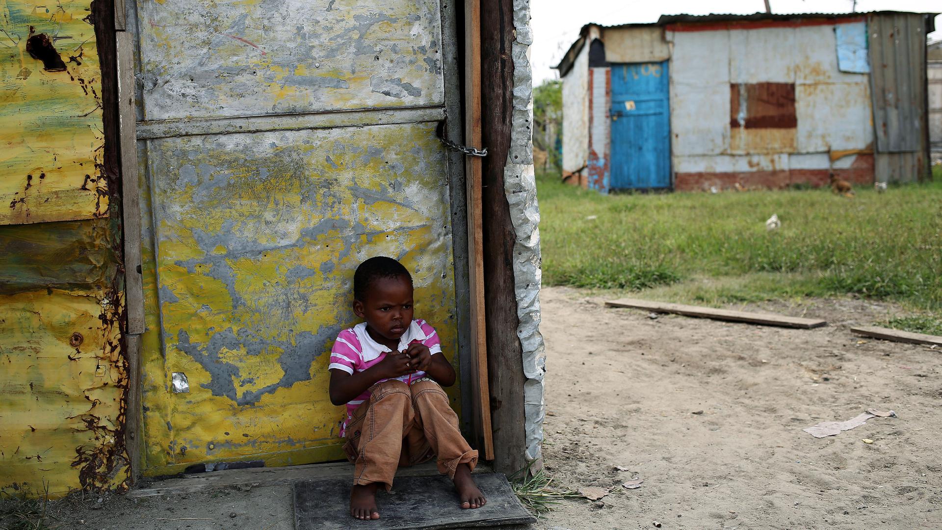 Afrikanischer Junge sitzt alleine in einem armen Dorf