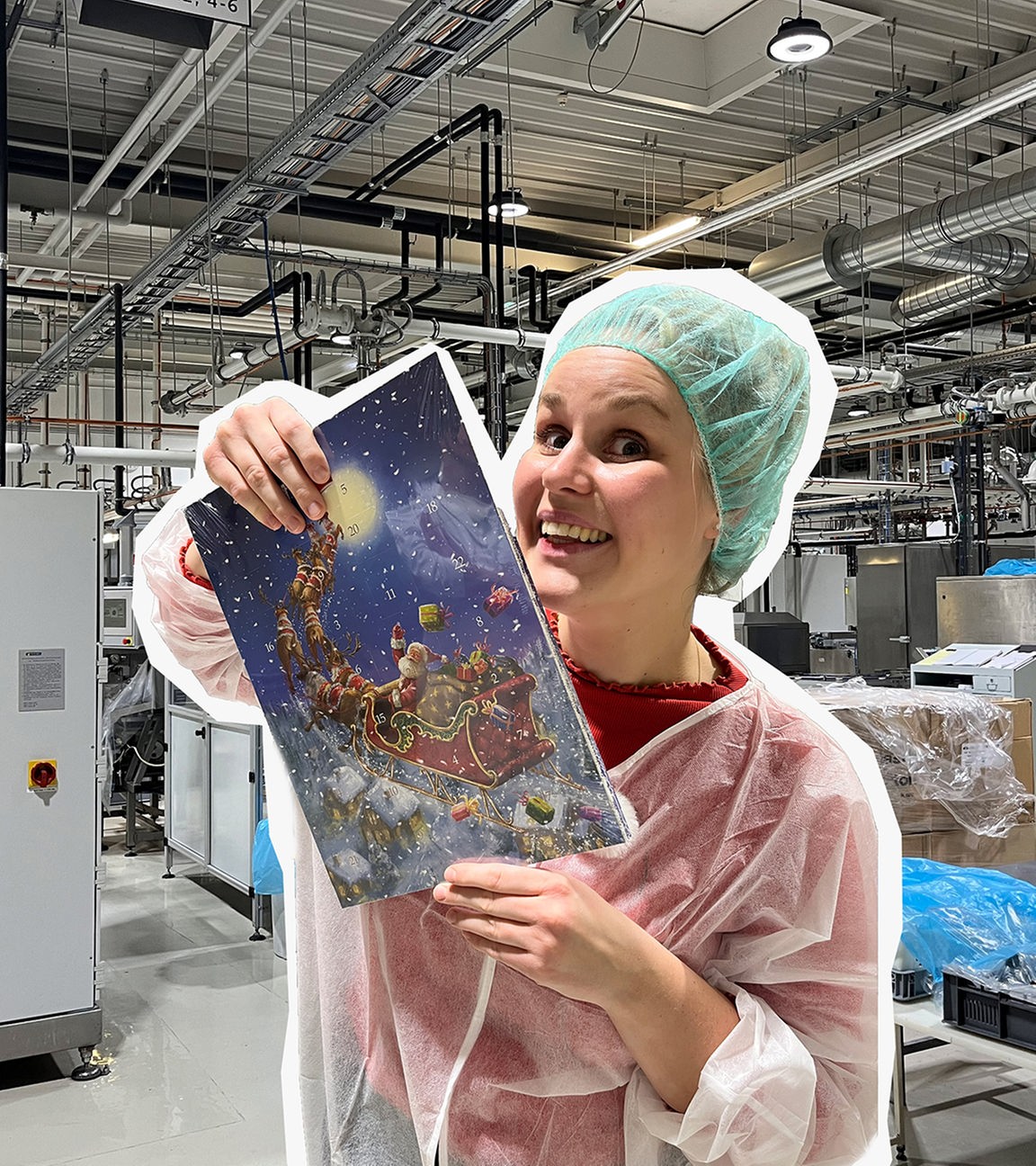 Auf dem Bild ist Reporterin Isabelle zu sehen. Sie hält einen Schokoadventskalender in der Hand. Im Hintergrund ist der Innenraum einer Fabrik zu erkennen.