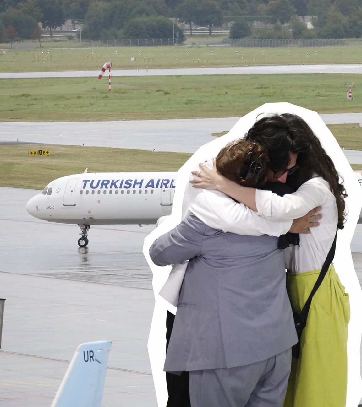 Eine afghanische Familie umarmt sich vor einem Flugzeug.