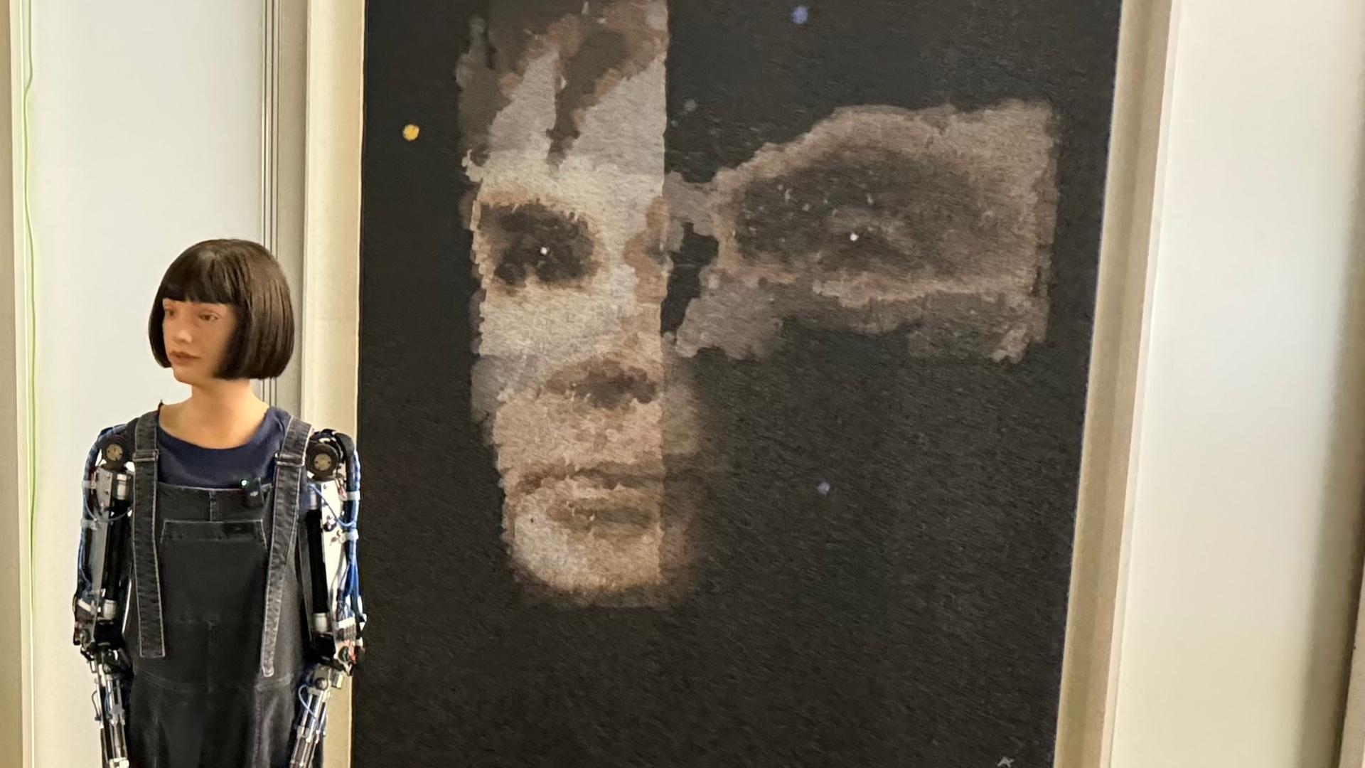 Ein weiblicher KI-Roboter steht vor seinem Gemälde, das versteigert wurde.