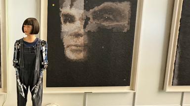 Ein weiblicher KI-Roboter steht vor seinem Gemälde, das versteigert wurde.