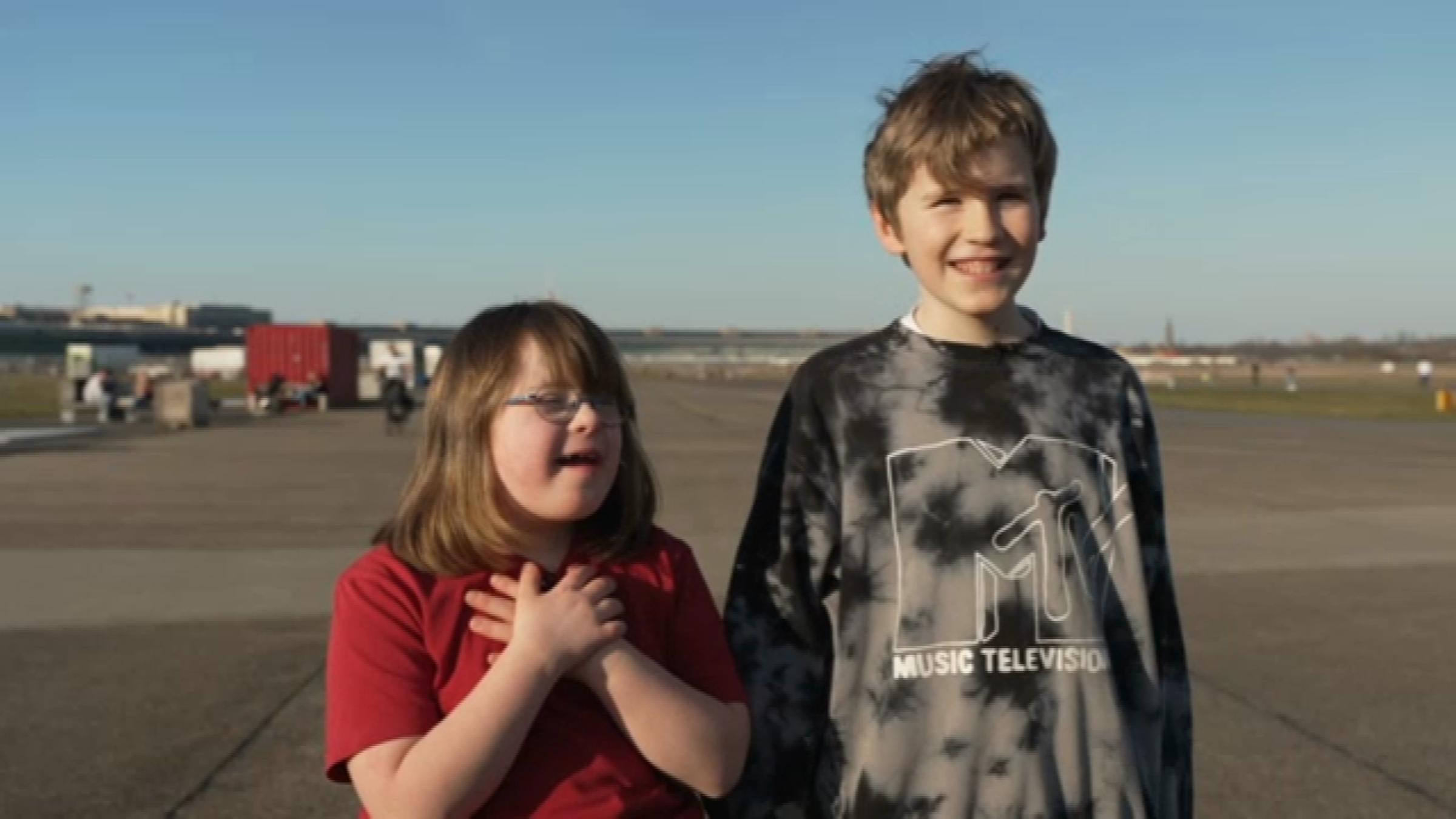 Alma und Jakob stehen nebeneinander und lachen. 