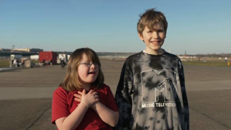 Alma und Jakob stehen nebeneinander und lachen. 