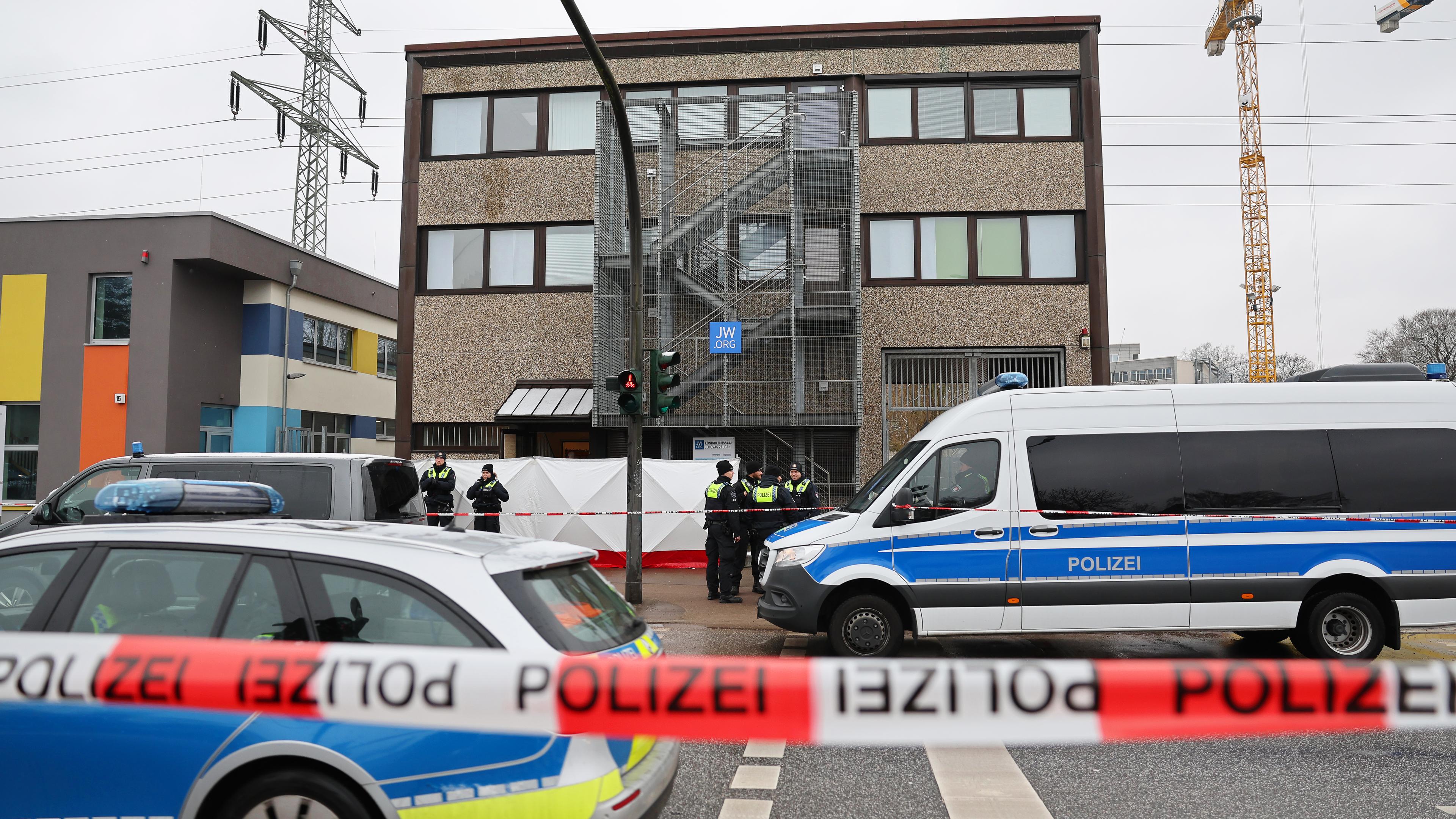 Im Mittelpunkt des Bildes ist ein Auto der Hamburger Polizei zu sehen; im Vordergrund verschwommen ein rot-weißes Absperrband.