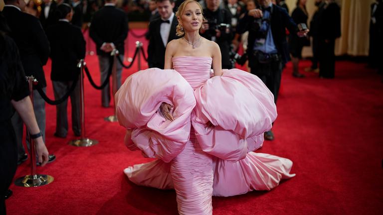 Ariana Grande posiert auf dem roten Teppich in einem pompösen rosanen Kleid.