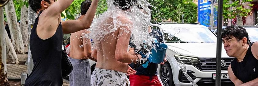 Menschen schütten sich Eimer voller Wasser über den Kopf. 