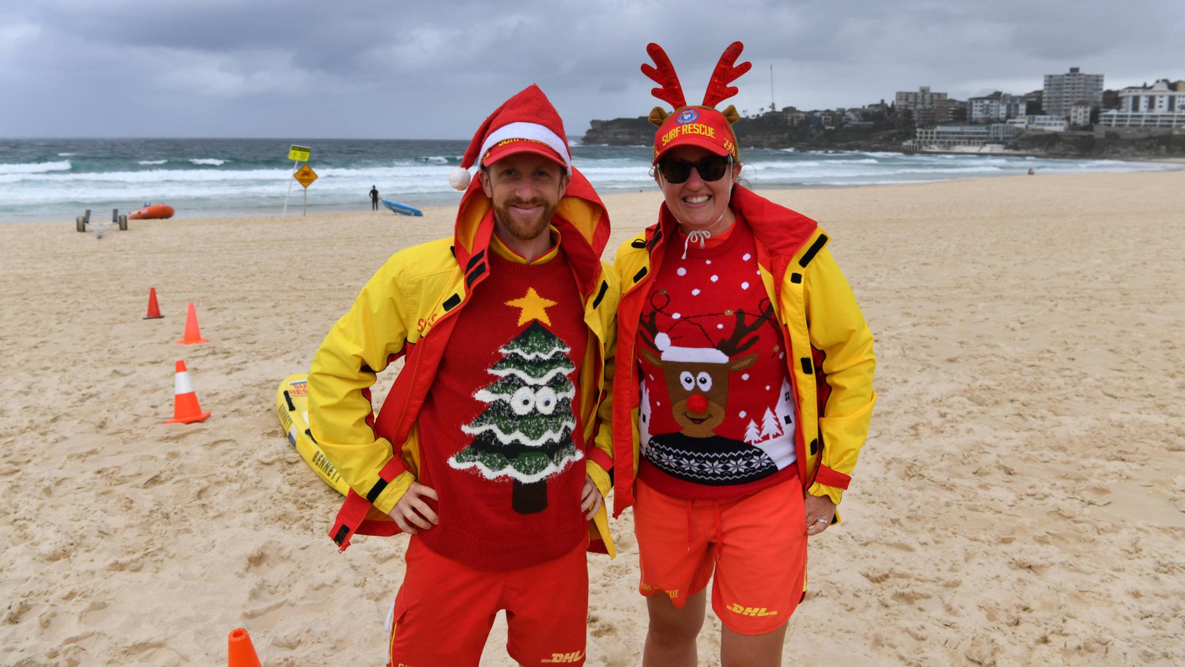 Rettungsschwimmer mit Weihnachtsmütze und -pullis am Strand.