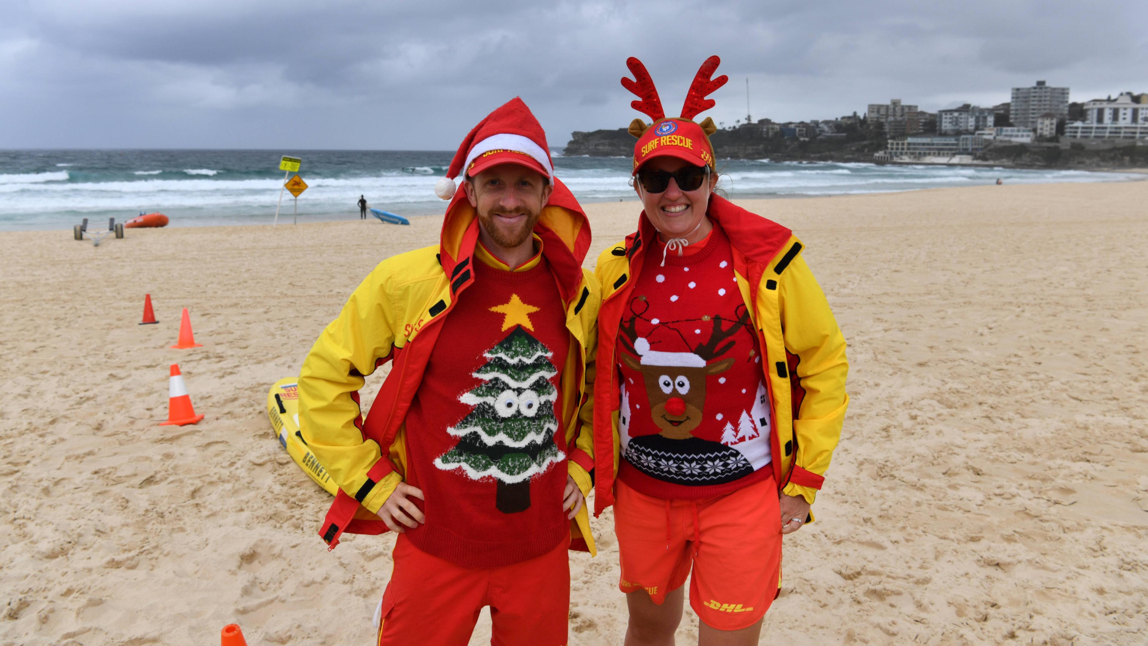 Rettungsschwimmer mit Weihnachtsmütze und -pullis am Strand.