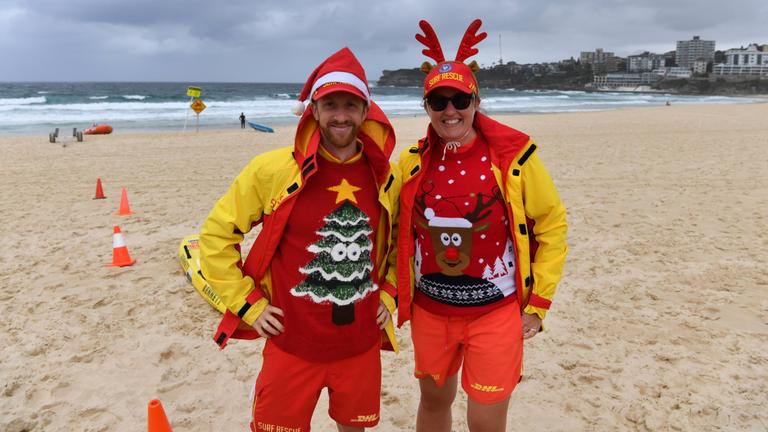 Rettungsschwimmer mit Weihnachtsmütze und -pullis am Strand.