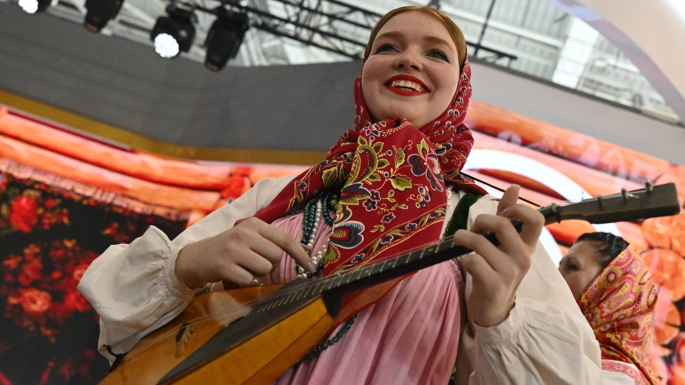 Eine Frau in traditioneller Kleidung spielt Balalaika.