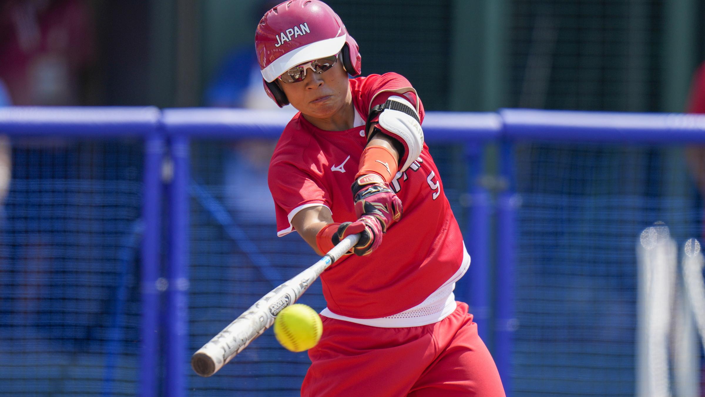 Ein Mann im roten Outfit schlägt einen Ball mit dem Schläger.