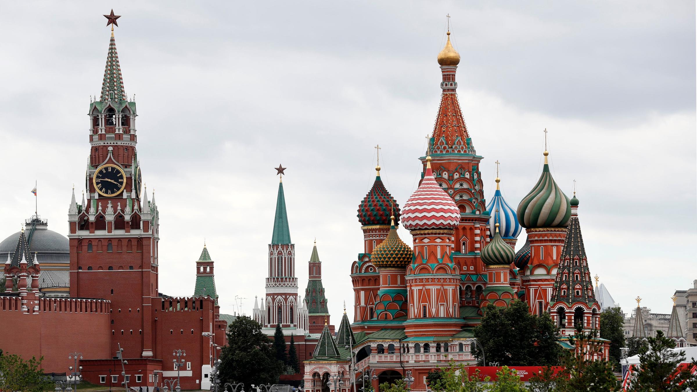 Man seht die Basilius-Kathedrale und den Kreml. Davor laufen Menschen. 