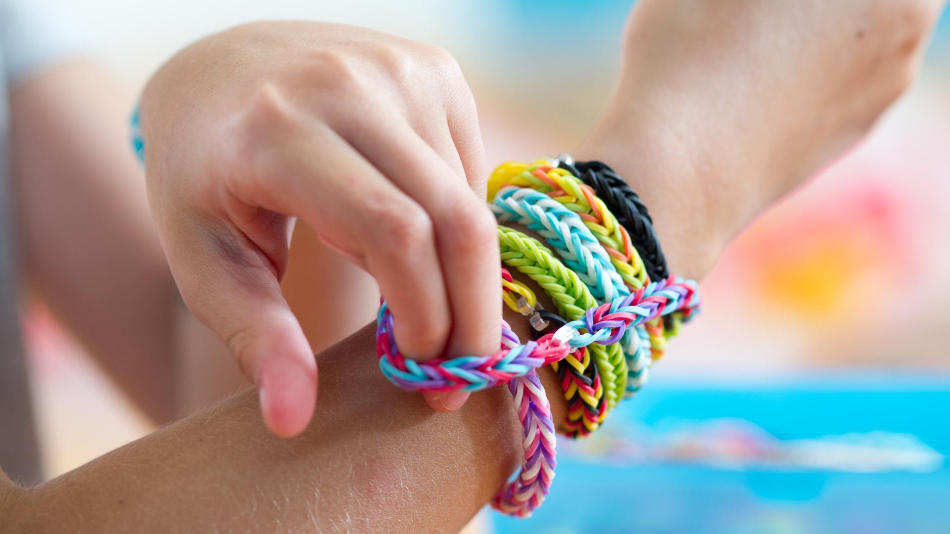 Auf dem Bild sieht man ein Kind mit einem geflochtenen Freundschaftsband am Arm.