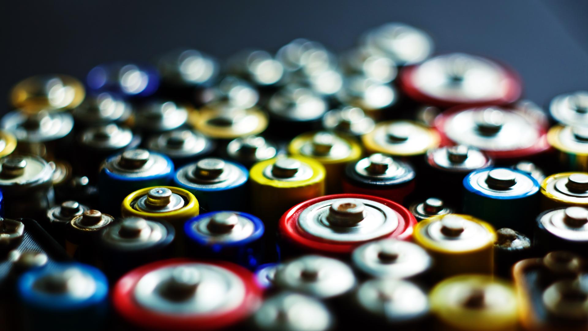 Batterien der gleichen Größe nebeneinander aufgereit, sind so fotografiert, dass man ihre runden Oberseiten sehen kann, aber keine Marke erkennt. 