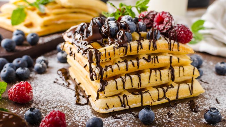 Belgische Waffeln auf einem Stapel mit Schokolade und Früchten