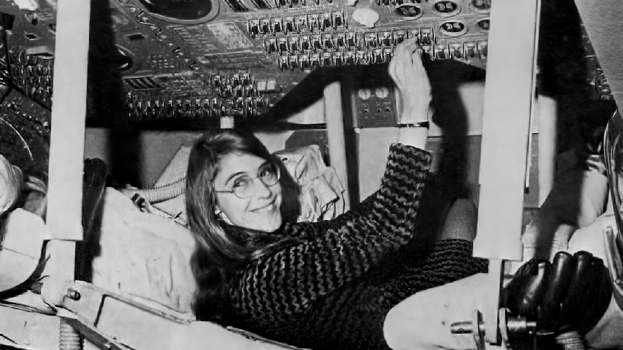 Die Wissenschaftlerin Margaret Hamilton sitzt in einer Raumfahrtskapsel und betätigt einige Knöpfe am Bordcomputer der Mondlandekapsel.