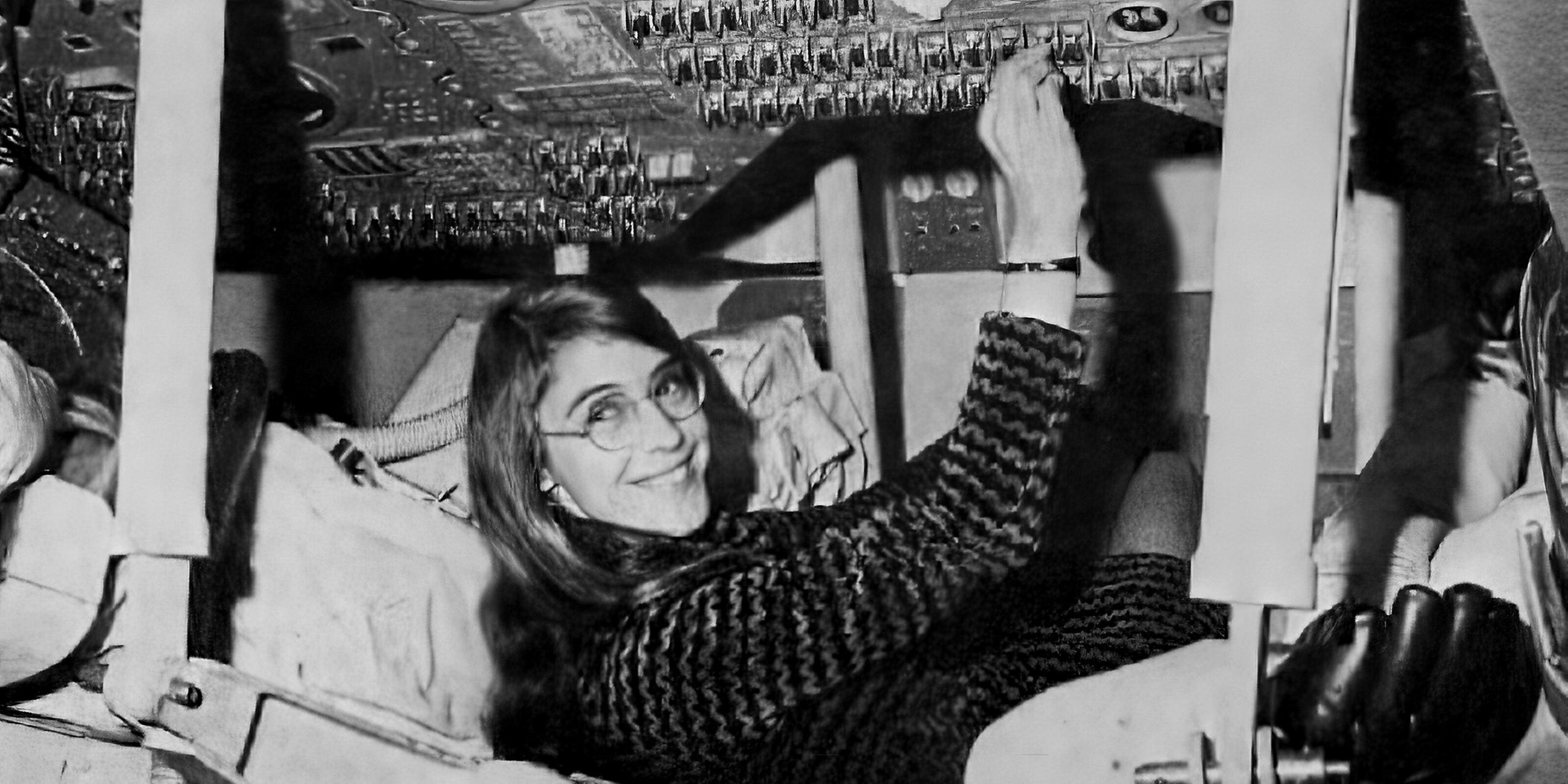 Die Wissenschaftlerin Margaret Hamilton sitzt in einer Raumfahrtskapsel und betätigt einige Knöpfe am Bordcomputer der Mondlandekapsel.