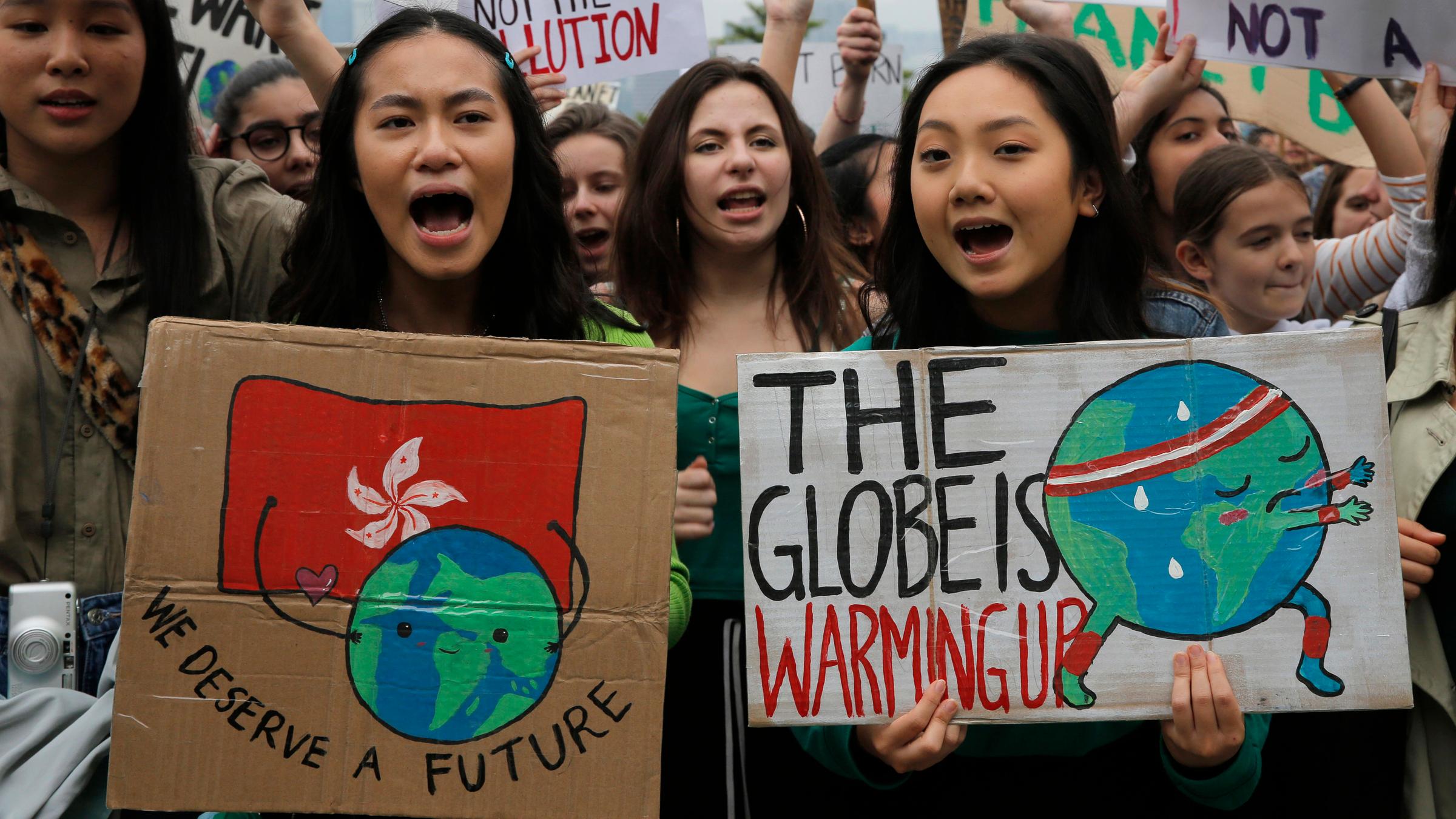 Zwei Demonstrantinnen halten Schilder mit der Aufschrift "The Globe is warming up" (auf deutsch: der Erdball wärmt sich auf) und "We deserve a future" (auf deutsch: Wir verdienen eine Zukunft) hoch