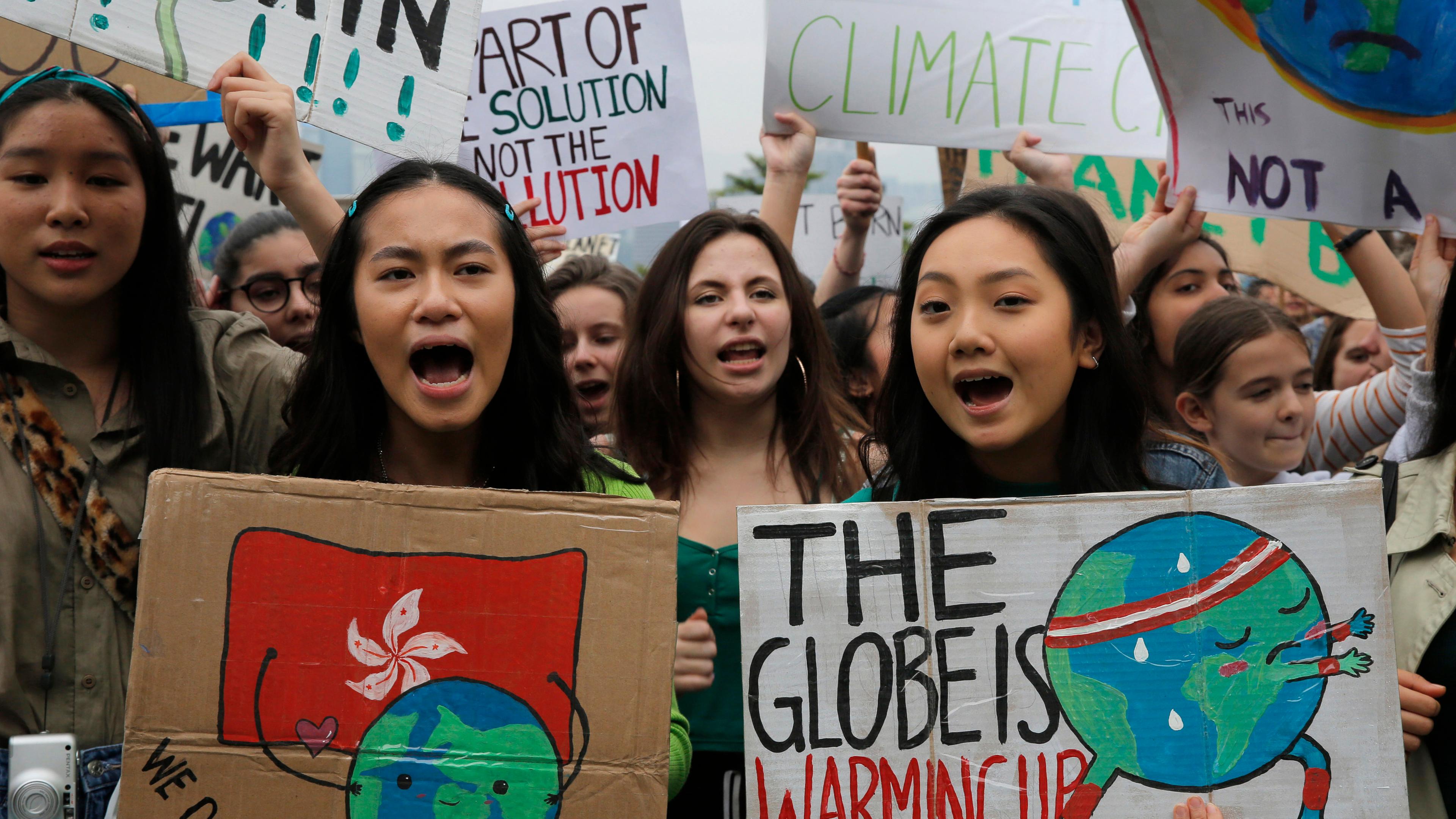 Zwei Demonstrantinnen halten Schilder mit der Aufschrift "The Globe is warming up" (auf deutsch: der Erdball wärmt sich auf) und "We deserve a future" (auf deutsch: Wir verdienen eine Zukunft) hoch