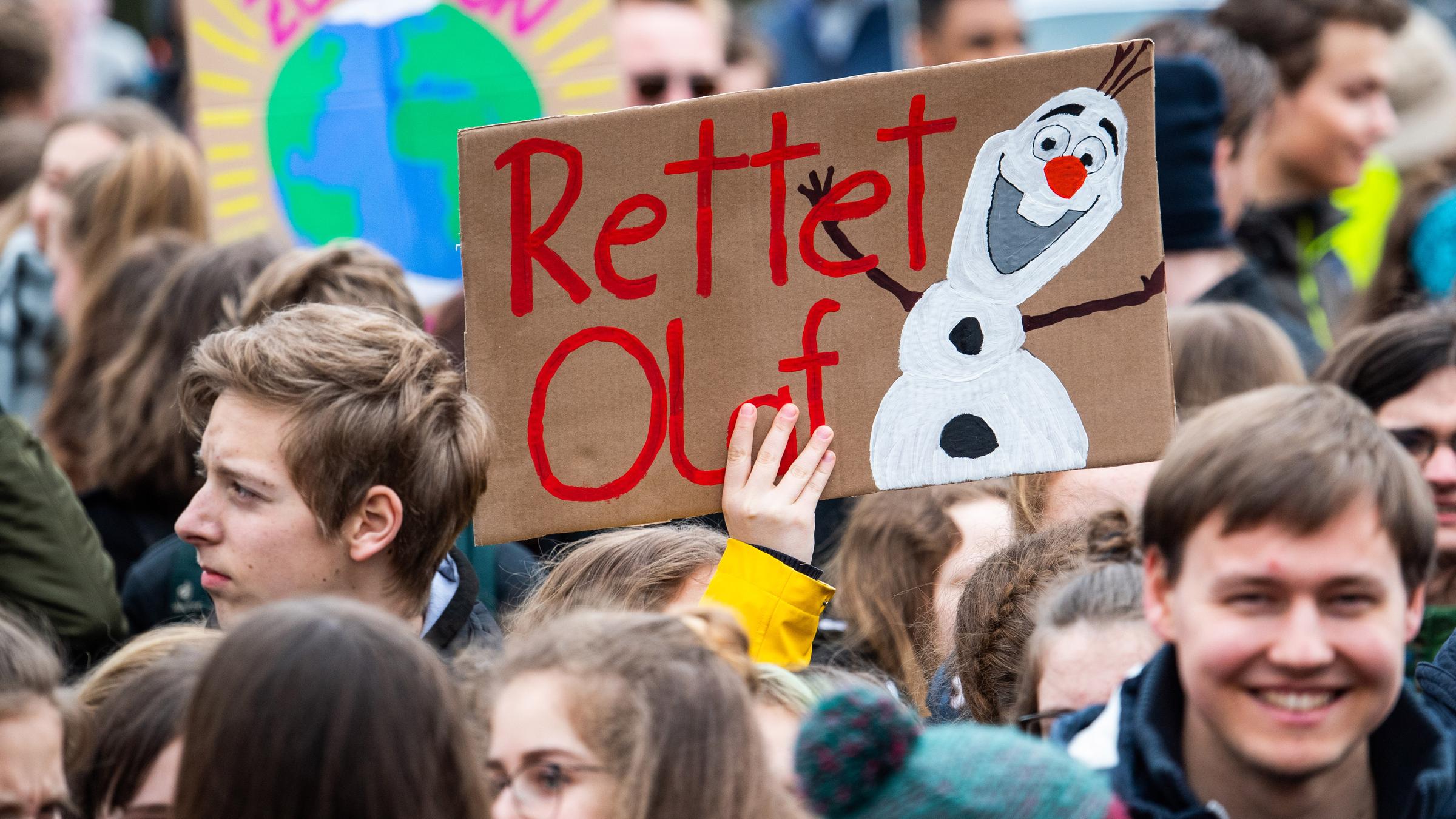 Eine Demonstrantin hält ein Schild mit der Aufschrift "Rettet Olaf", der bekannten Schneemannfigur "Olaf" aus dem Disneyfilm "Die Eiskönigin", hoch.