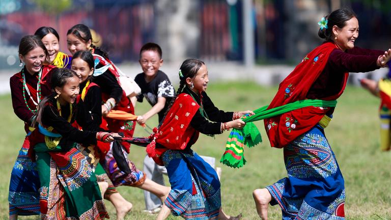 Kinder spielen in bunten Gewändern bei einem traditionellen Fest in Nepal.