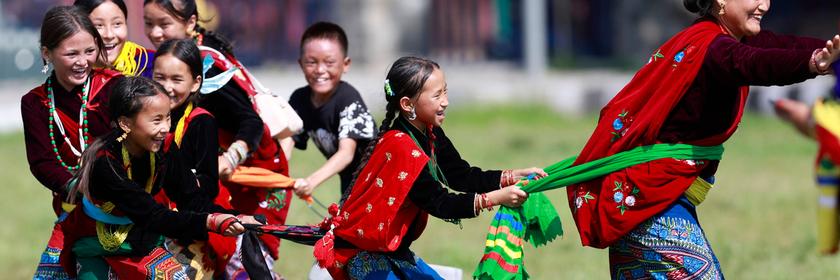 Kinder spielen in bunten Gewändern bei einem traditionellen Fest in Nepal.