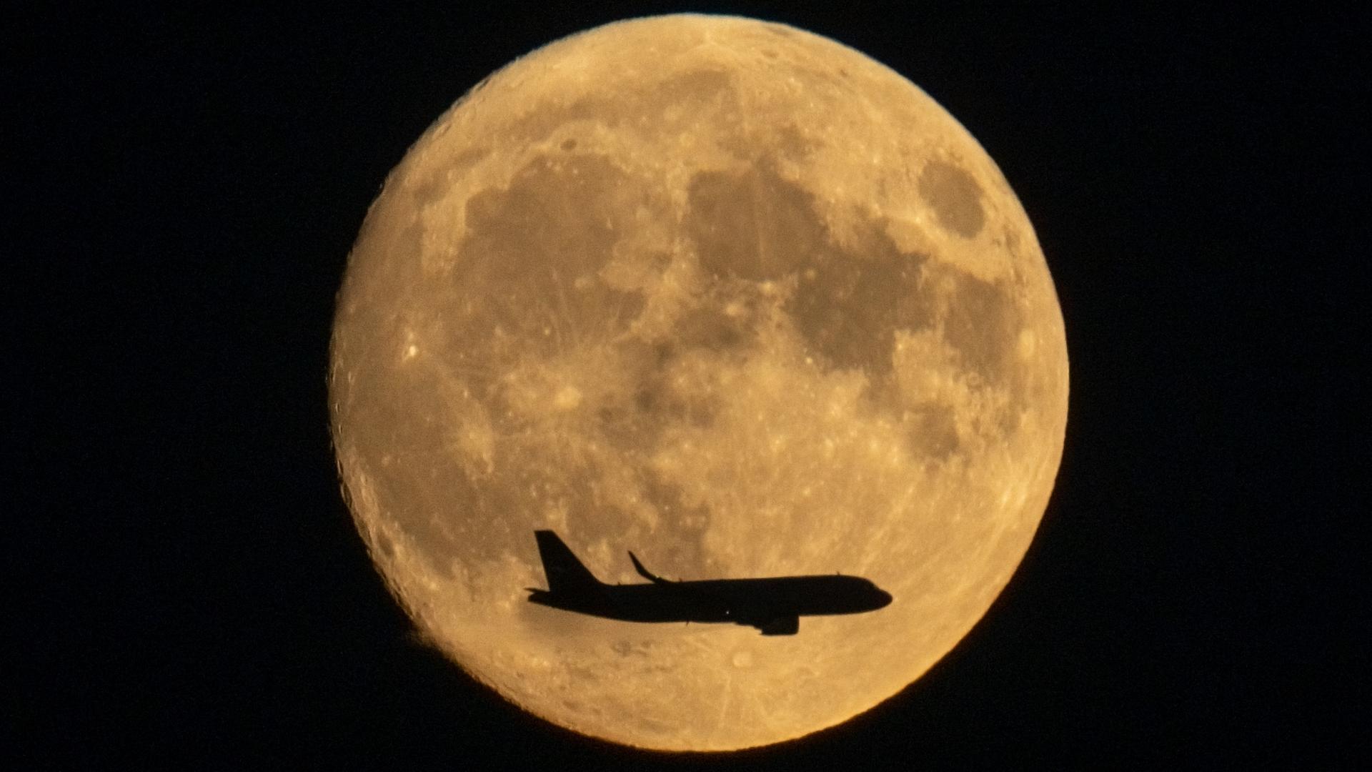 Flugzeug fliegt vor Vollmond