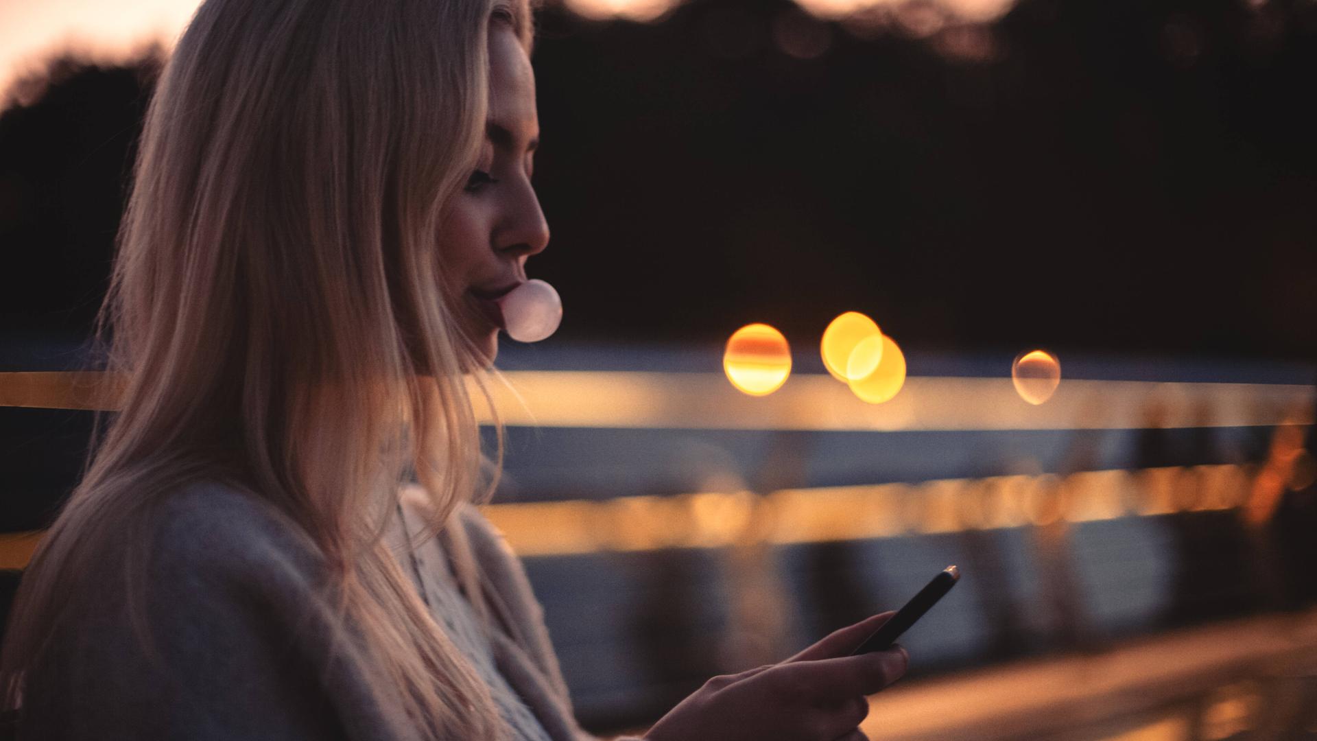 Jugendliche kaut Kaugummi und sitzt am Handy