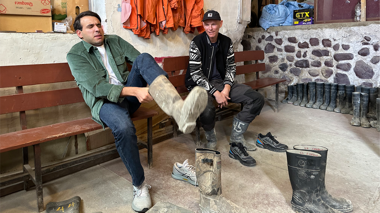 logo!-Reporter Sherif sitzt neben Mann auf Bank und hebt das Bein, während er einen Stiefel anzieht.