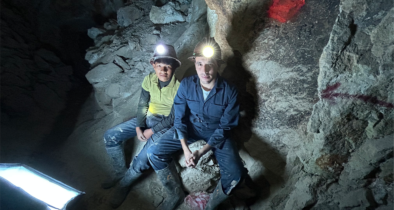 logo!-Reporter Sherif und Kind sitzen mit leuchtenden Helmlampen in Mine und schauen in die Kamera