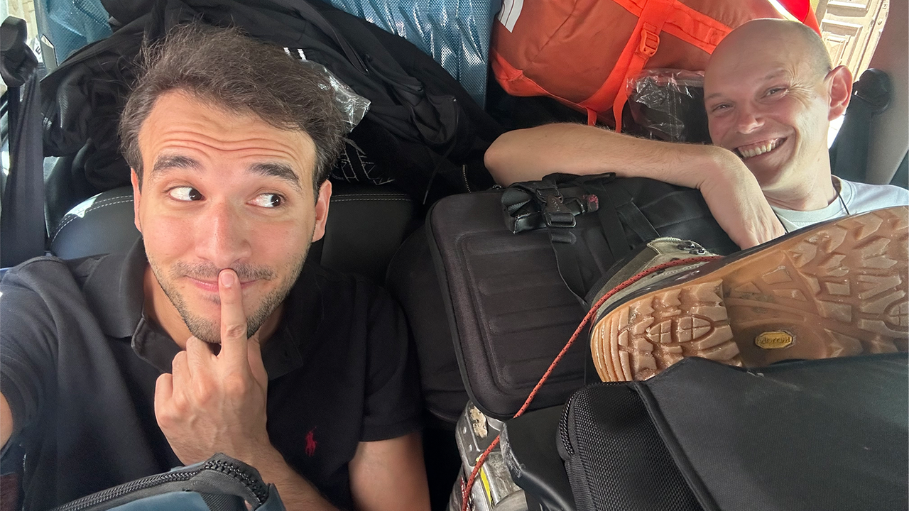 logo!-Reporter Sherif neben Mann in mit Koffern und Taschen zupacktem Auto