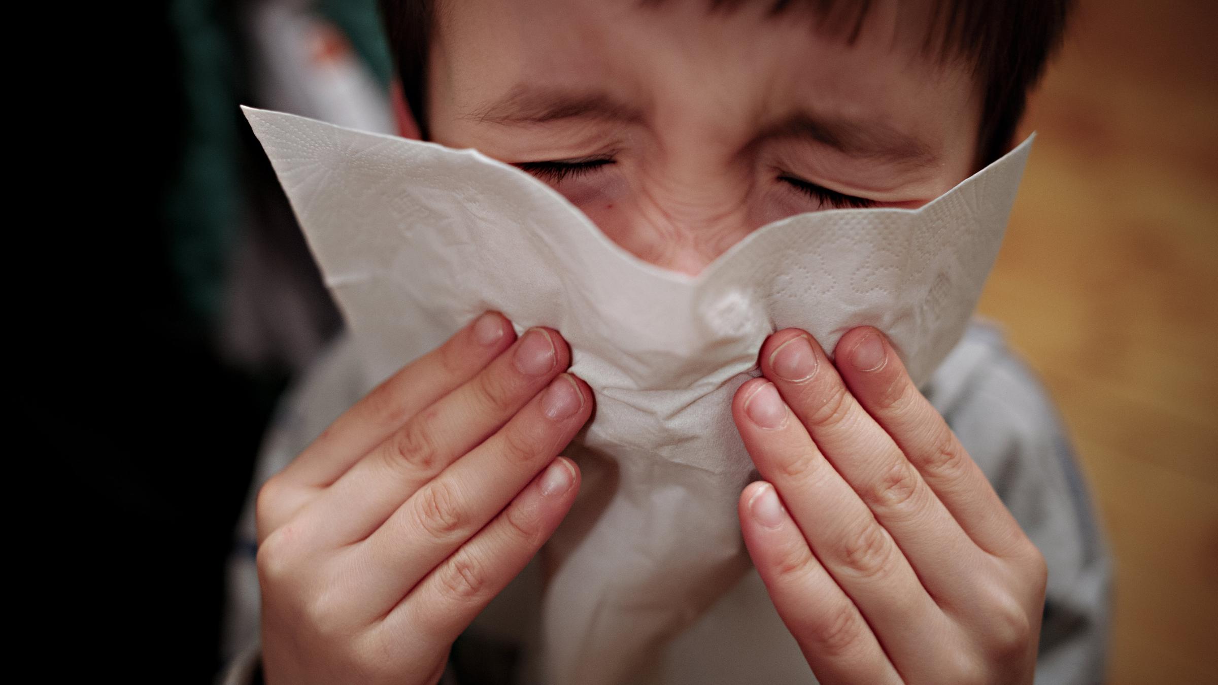 Ein Junge putzt sich die Nase.