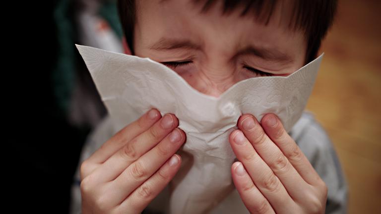 Ein Junge putzt sich die Nase.