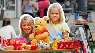 Zwei mädchen, die hinter ihrem verkausstand auf dem Flohmarkt stehen. 