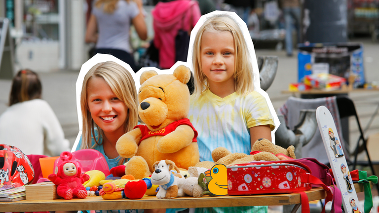 Zwei mädchen, die hinter ihrem verkausstand auf dem Flohmarkt stehen. 