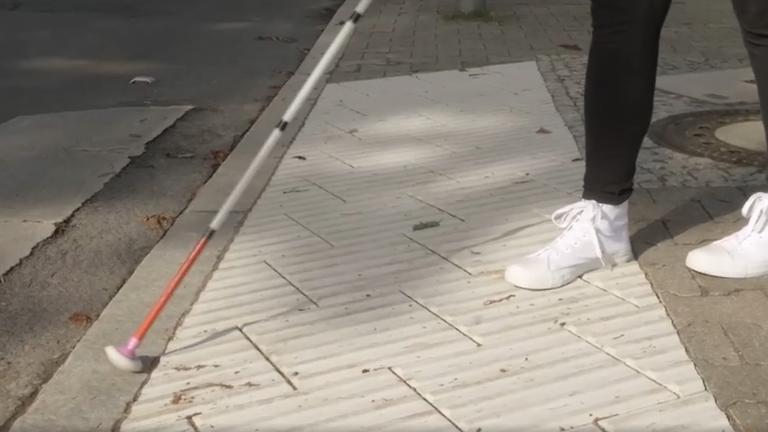 Junge Frau orientiert sich mit ihrem Blindenstock