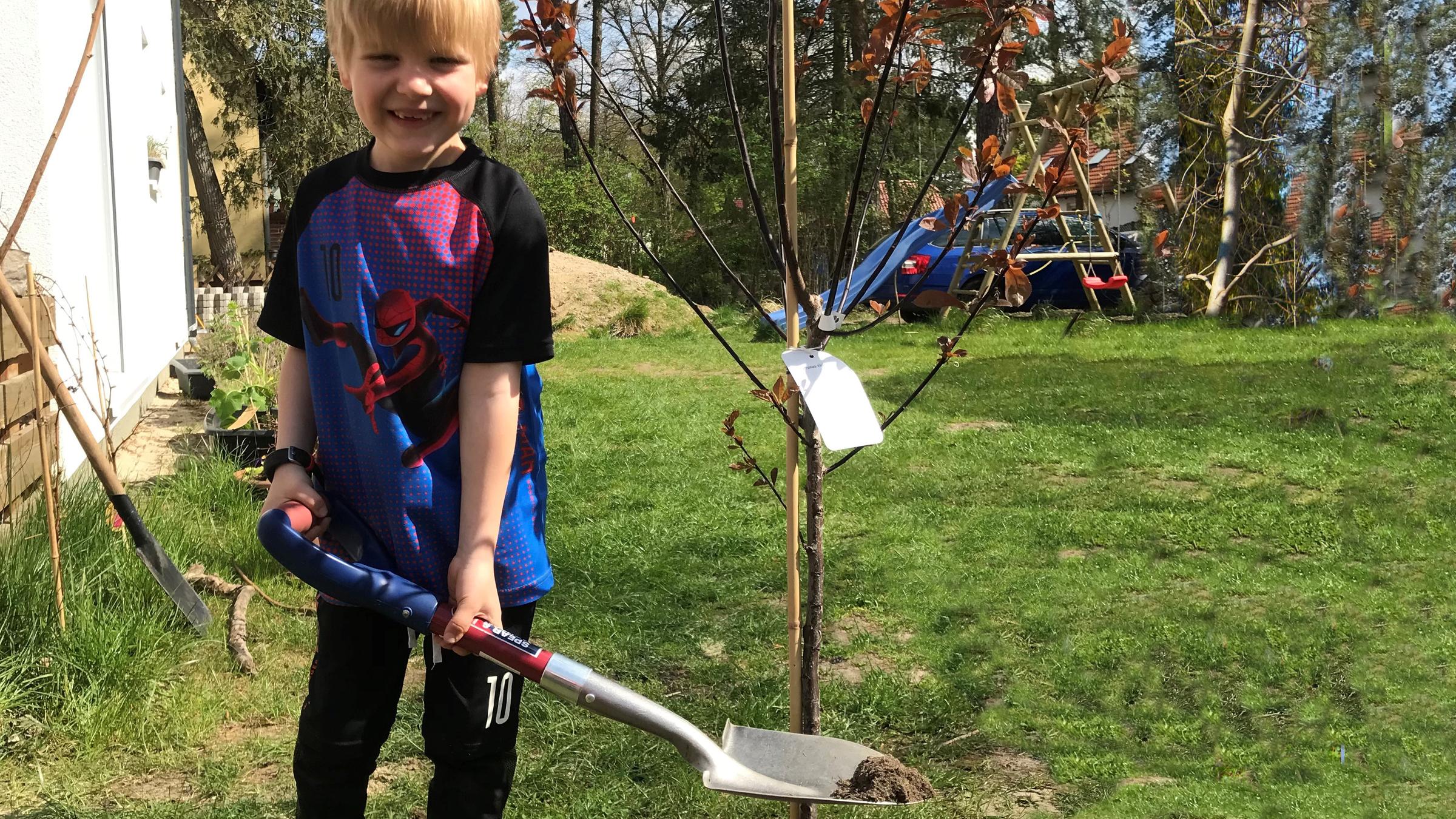 Mats mit Schaufel neben seinem frisch eingepflanzten Baum