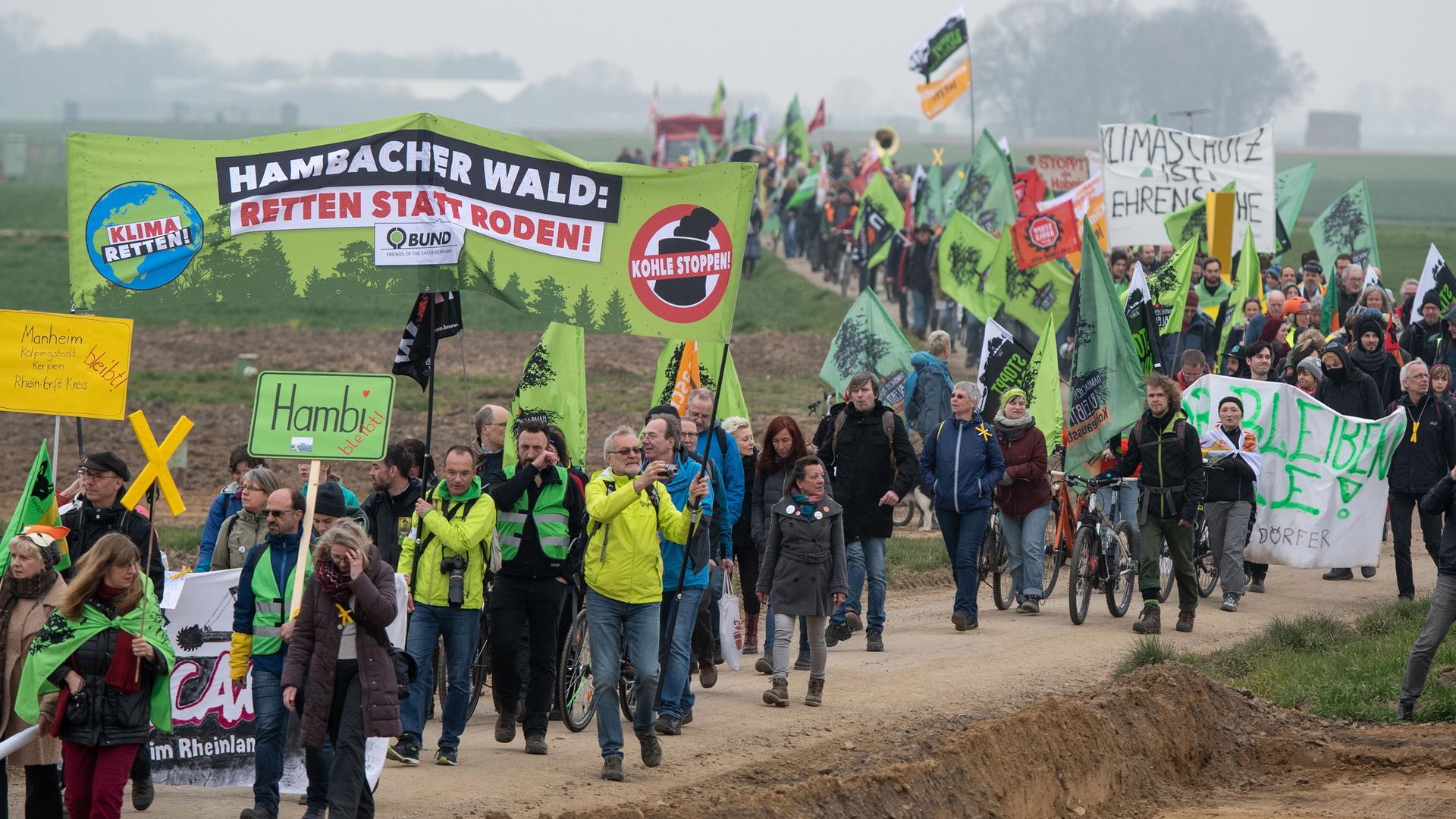 Eine Demonstration mit vielen Menschen. Auf einem Banner ist zu lesen: "Hambacher Wald – Retten statt roden".