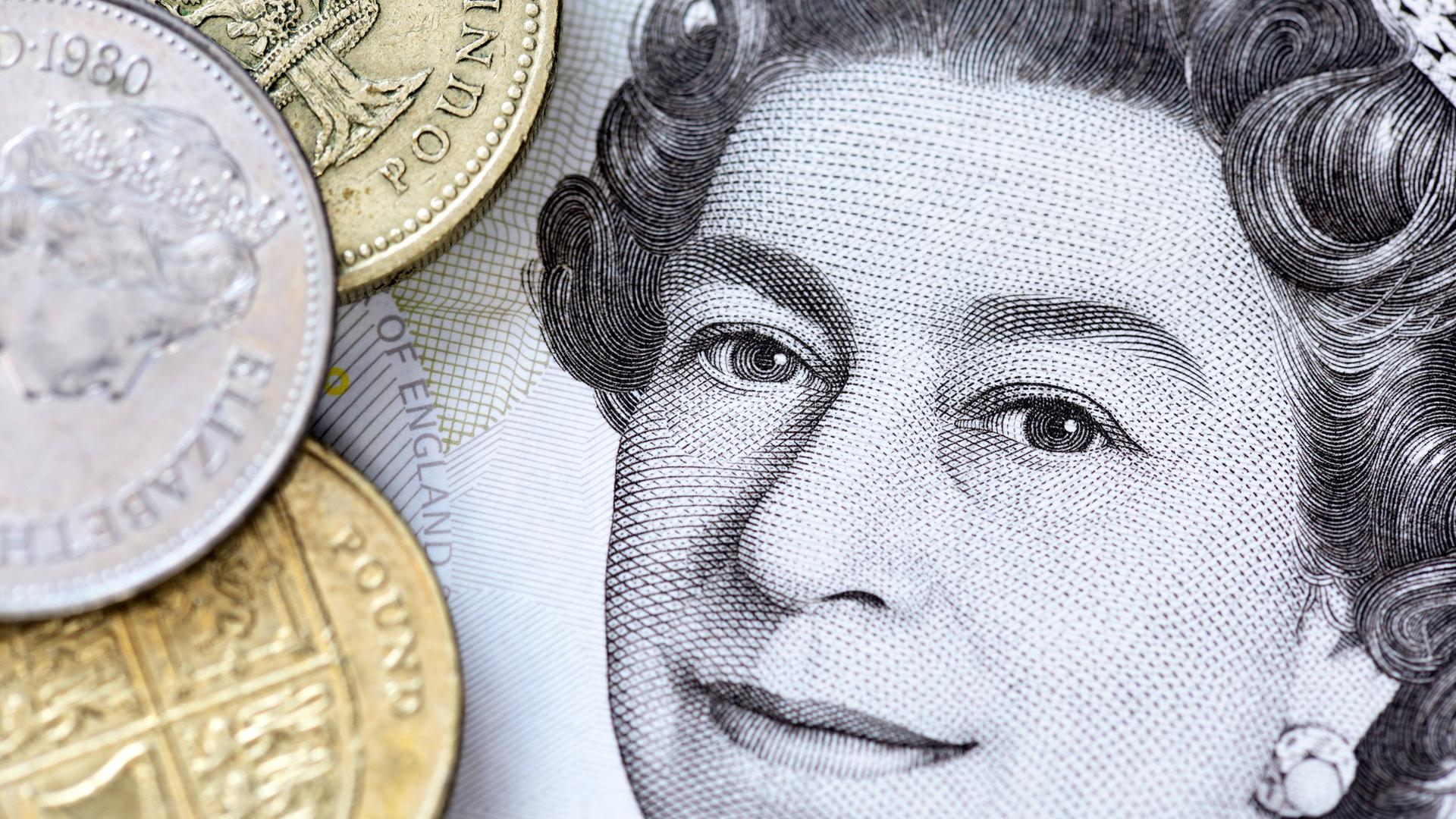 Portrait von Queen Elizabeth II. auf einer britischen Fünf-Pfund-Note und Pfundmünzen
