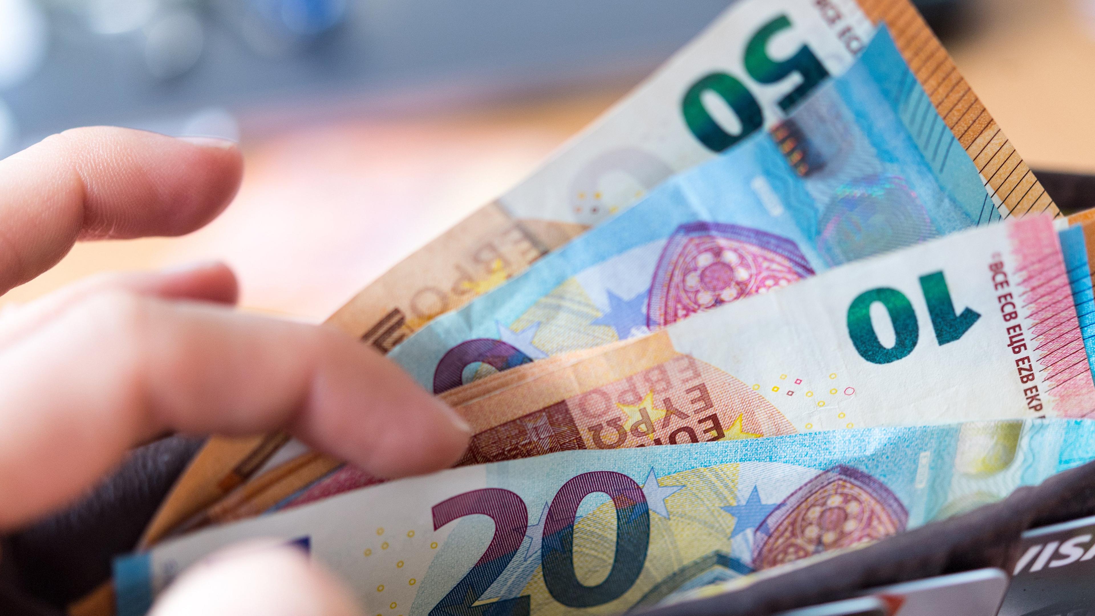 Sachsen, Dresden: Eine Frau hält eine Geldbörse mit Banknoten in der Hand.