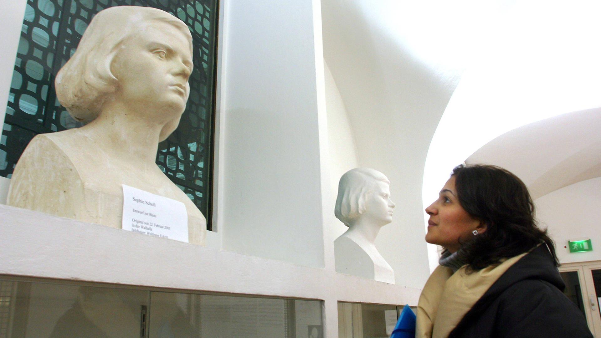 Eine Frau betrachtet eine Büste von Sophie Scholl