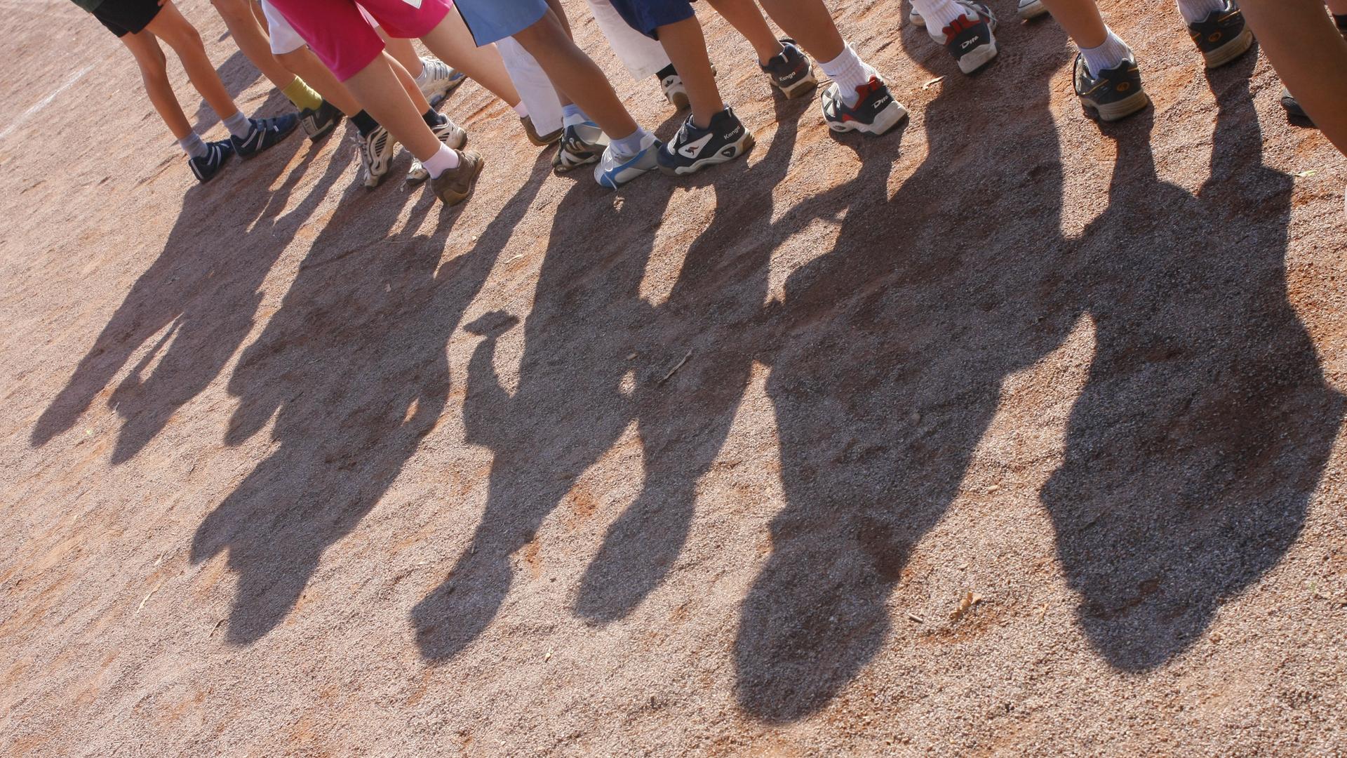Schatten von Kindern auf Sportplatz bei Bundesjugendspielen. 