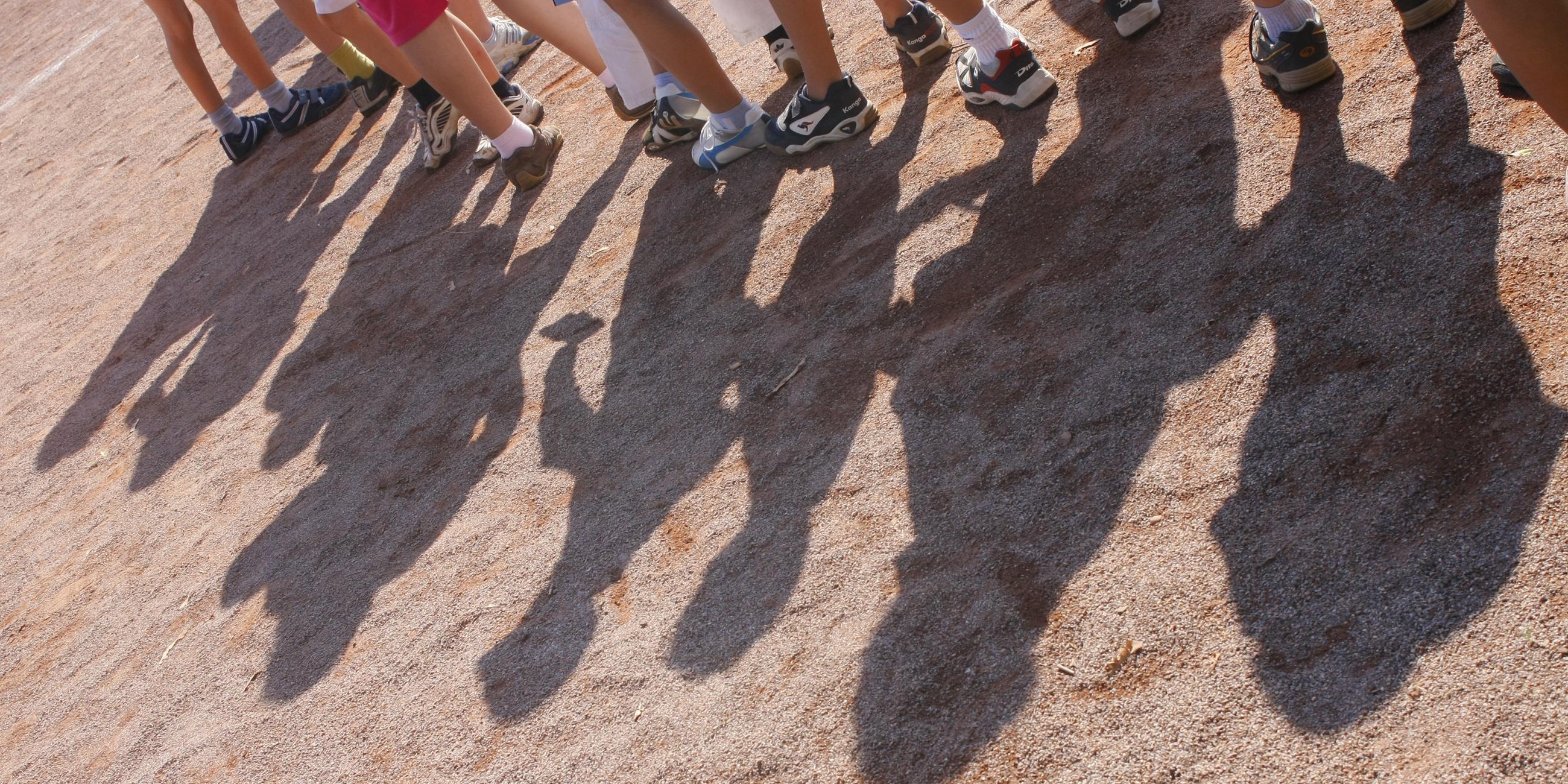 Schatten von Kindern auf Sportplatz bei Bundesjugendspielen. 