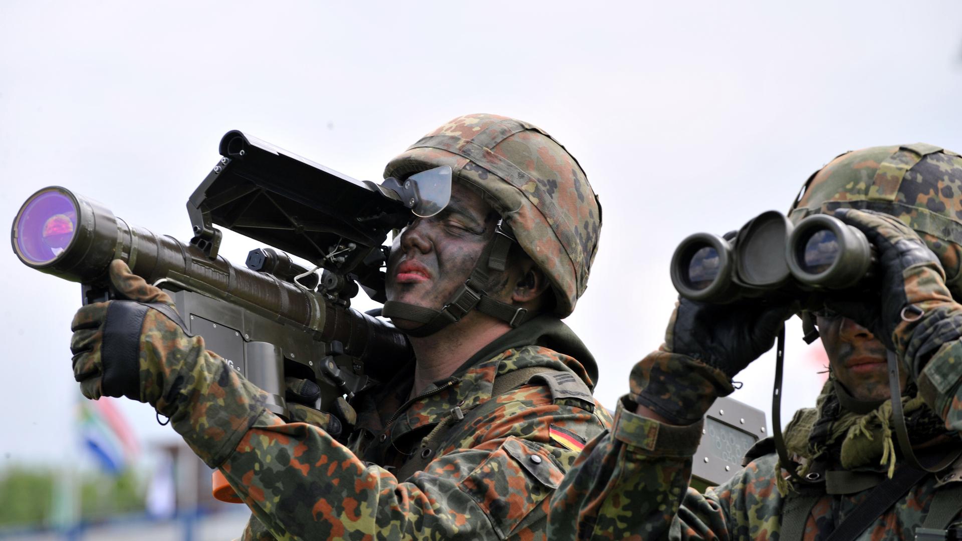 Zwei Soldaten, einer mit Fernglas, der andere hält eine Flugabwehrrakete vom Typ "Stinger". 