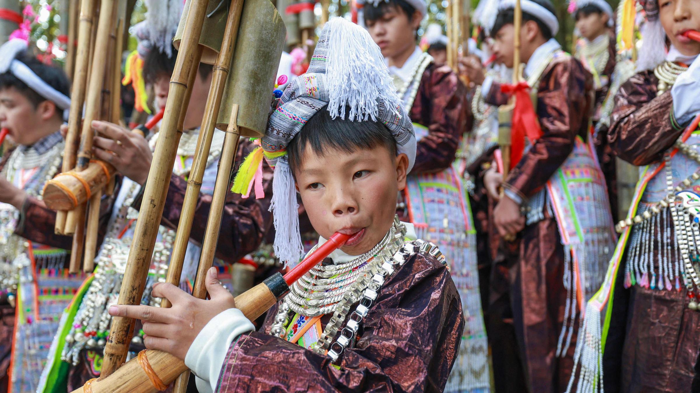 Ein chinesischer Junge spielt auf einem Instrument während eines traditionellen Festes