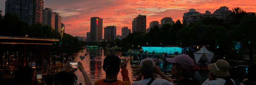 Menschen machen ein Foto von einem Sonnenuntergang in Peking. 