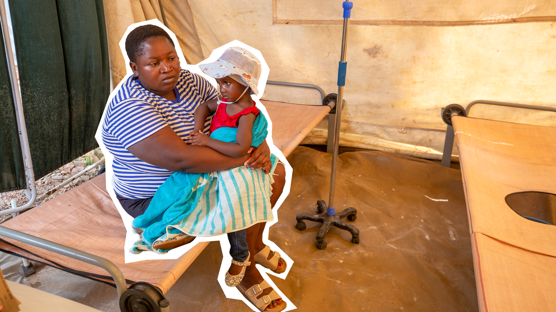 Mutter mit Tochter auf dem Arm sitzt in einem Zelt.