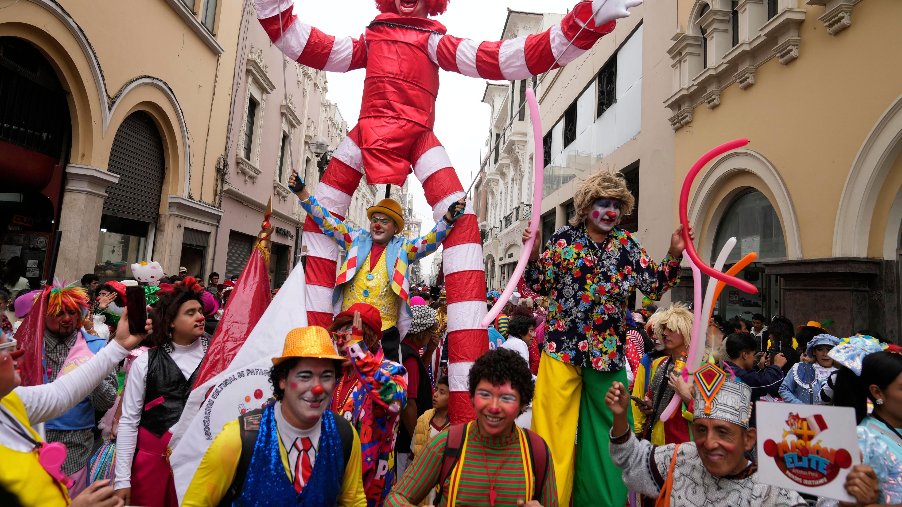 Eine Parade bestehend aus Clowns zieht durch eine Altstadt