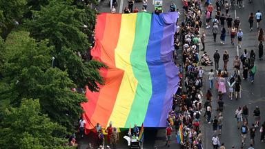 Menschen tragen eine riesige Regenbogenflagge durch Berlin 
